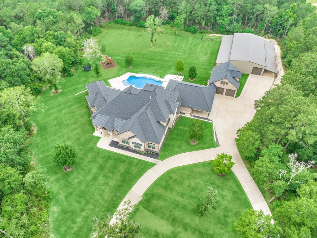 Drone shot of a large gated community home with a pool.