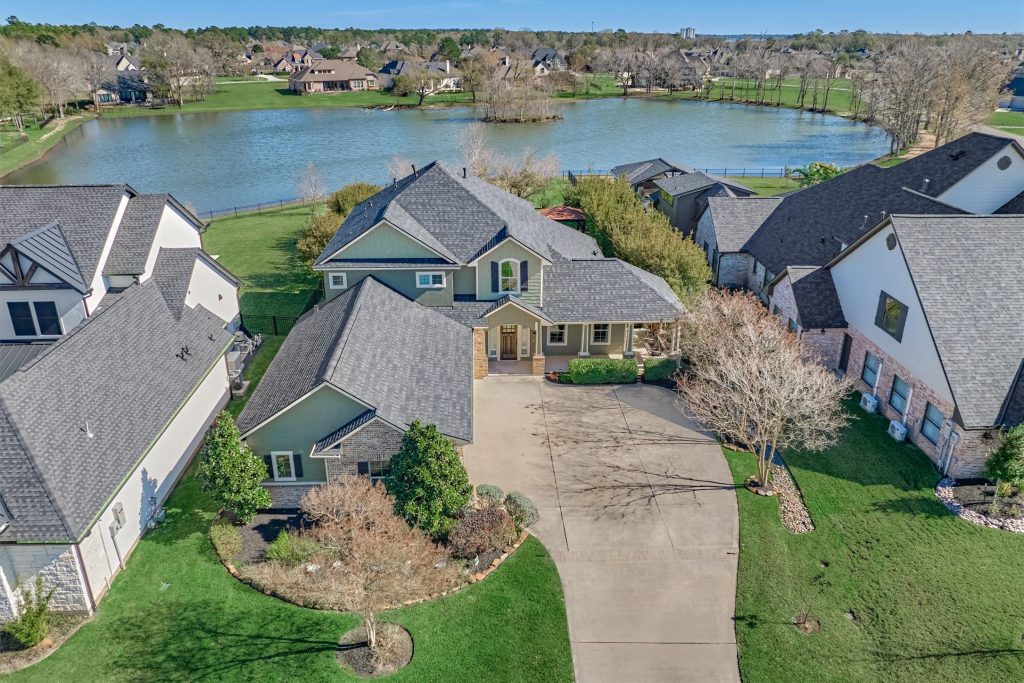 Drone shot of a large lake house with waterfront scenery behind it.