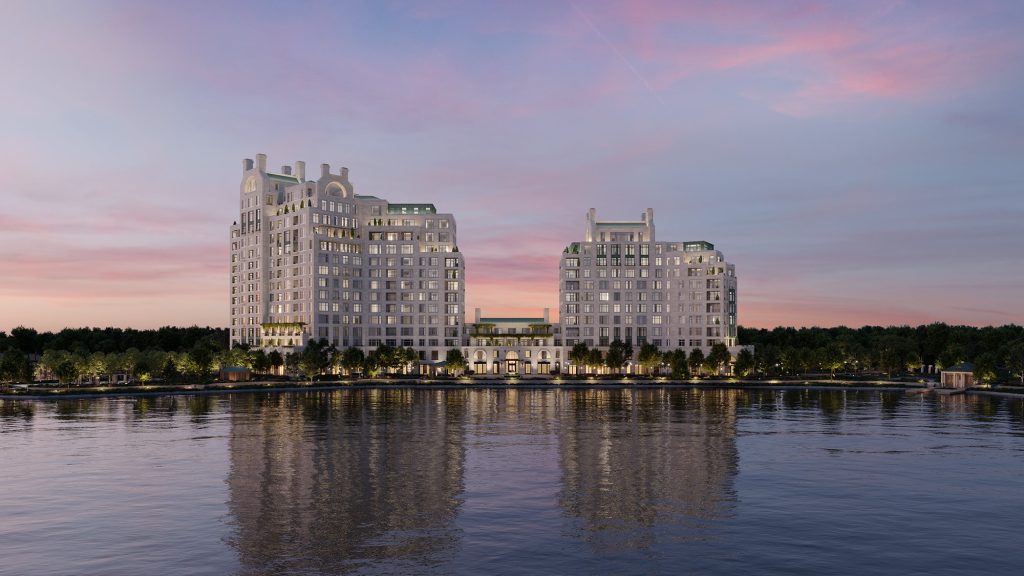 Wide shot of luxury condos along the lake lit up before sunset.