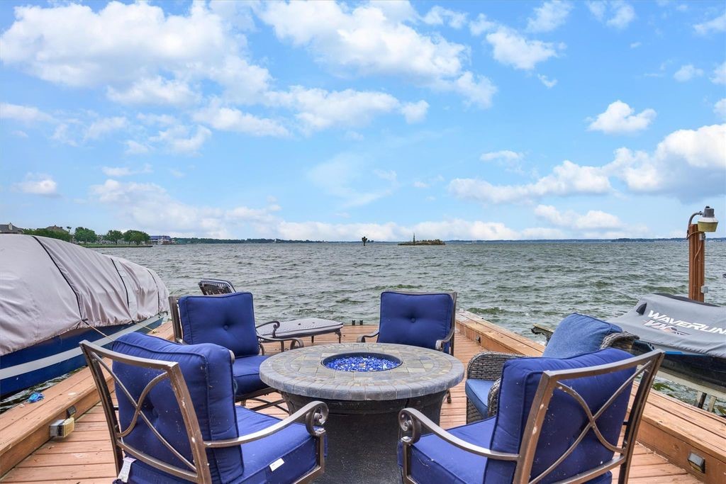 Patio chairs around a fire pit on the dock with the lake in the background.