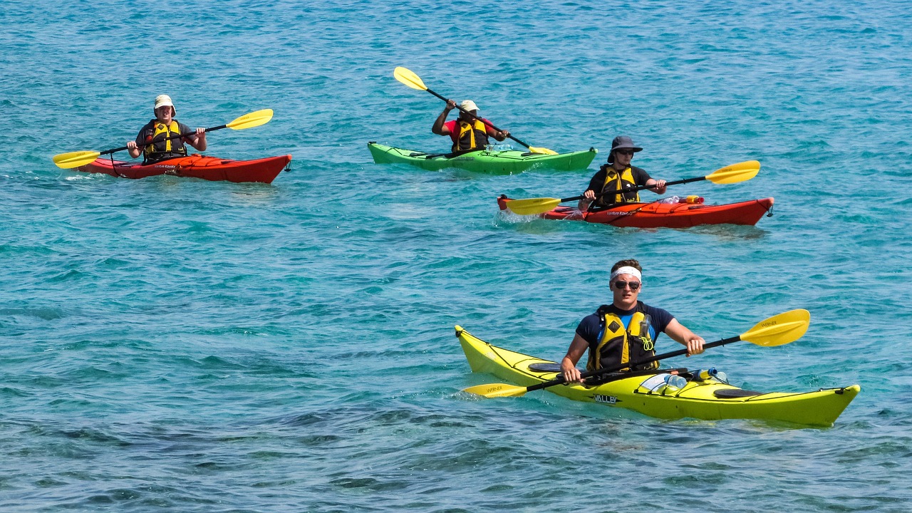 A group of four friends kayaking in blue water on the lake. 